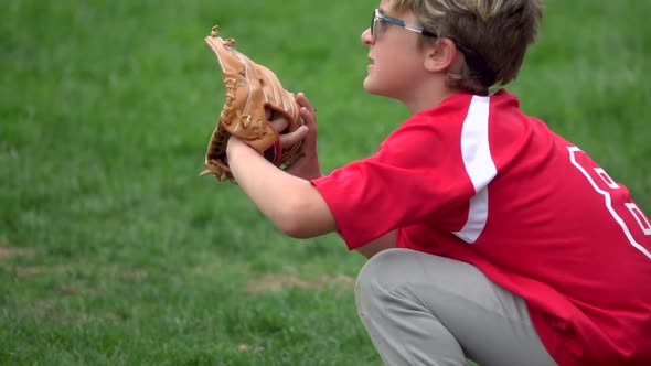 A boy practices playing catch on a little league baseball field. alt