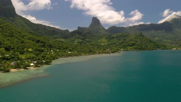 Aerial shot flying over turquoise color sea towards Mo'orea island coastline in French Polynesia alt