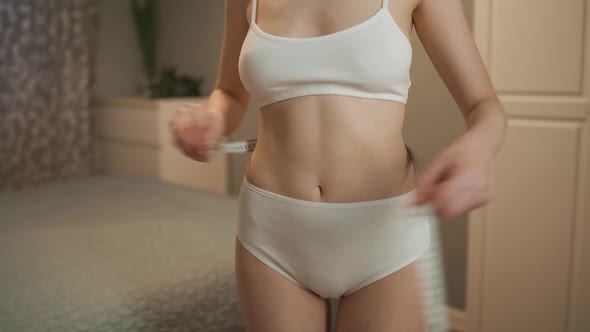 Standing in Her Room a Girl Measures Her Waist alt