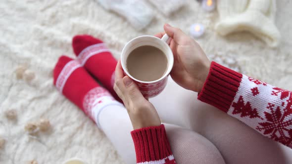 Woman Hands Holding a Cup of Hot Cocoa on the Background of a Garland in the Christmas Decorations