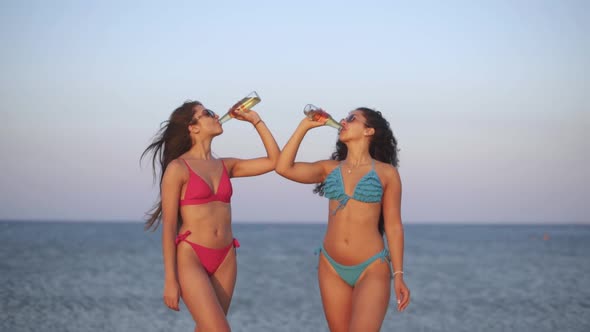 Happy Young Multiethnic Women Drinking Beer on Beach at Sunset