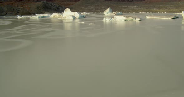 Wide aerial helicopter flying around US Army National Guard blackhawk helicopters sitting on tarmac  alt