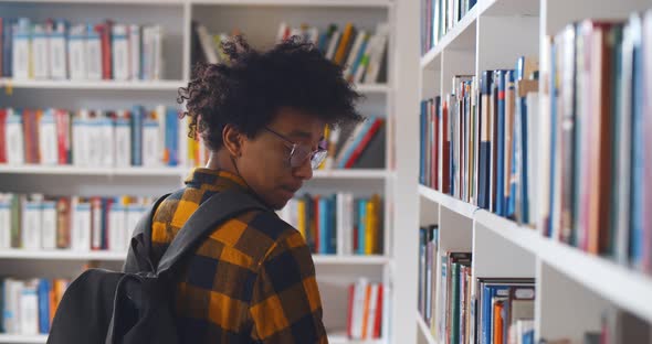 Back View of Young Happy African Student Looking Around in Modern Library alt