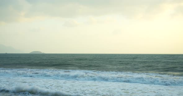 A Large Sun Appears From Behind the Clouds and Large Mountains Touch the Horizon and Coast alt