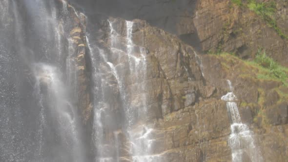Waterfall By Wet Stones Appears From Behind Brown Rock alt