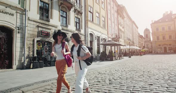 Women Tourists with Backpacks Walking in Downtown