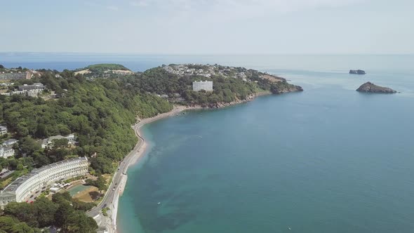 Flying over a busy road along the coastline of Torquay, England. In the distance is a massive hotel. alt