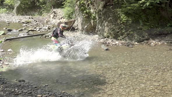 Enduro Athlete on a Motorcycle Crosses a River