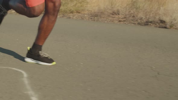 Male black legs run along road in sneakers. Legs run along the road on ...