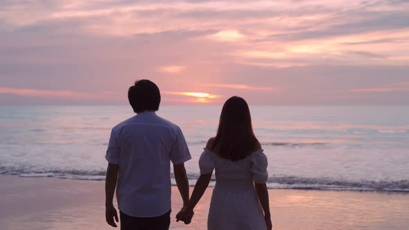 Young Asian couple holding hand together and looking beautiful sunset