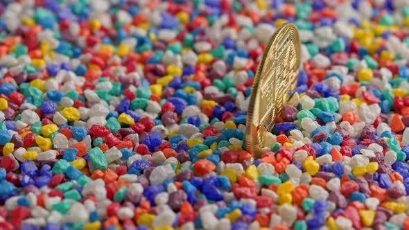 Bitcoin Coin Standing in Colored Stones on Flat Surface Slowly Rotating