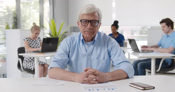 Mature Executive Consulting Client Remotely Online in Modern Office Looking at Camera alt