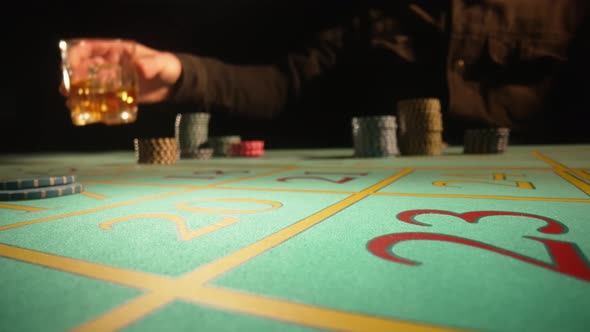 Unrecognizable Male Gambler Makes Bets While Sitting at Roulette Table in Casino alt