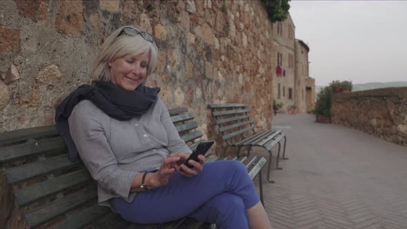 Senior woman using smart phone on bench