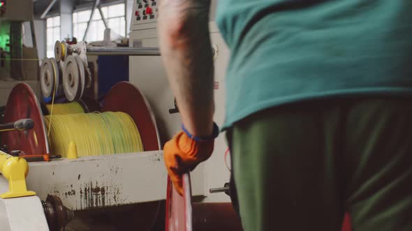 Unrecognizable Worker Rolls a Reel with Cable in Cable Production Plant Close Up