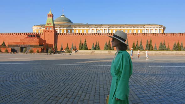 Beautiful girl in a green dress on an empty Red square alt