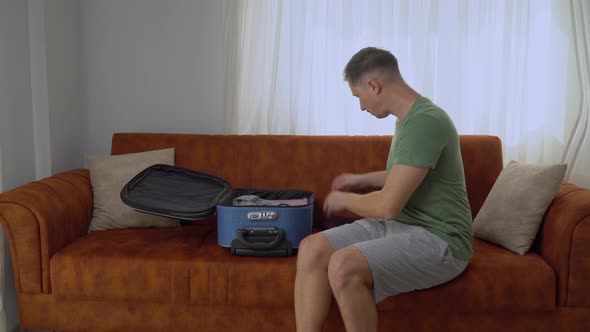 A Man Packs a Suitcase on a Business Trip Carefully Folds Clothes and a Laptop Into Hand Luggage