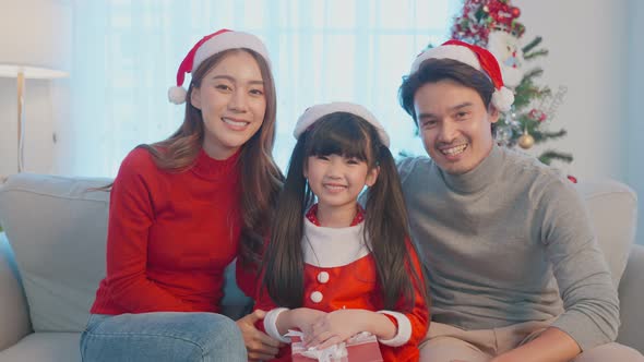 Portrait of Asian happy family wear Santa hat, sit in living room ready to celebrate xmas in house. alt