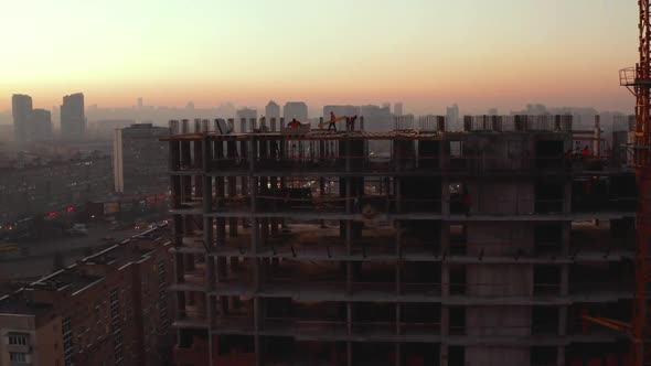 In the Background Working Crane and City. Aerial Shot of the Building in the Process of Construction