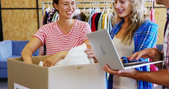 Man working on laptop while volunteers sorting clothes of donation box alt