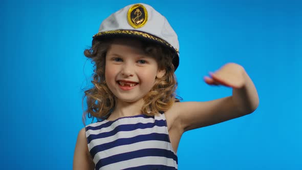 Little Curly Sailor Girl Puts Her Hand to the Cap and Smiles in the Studio alt