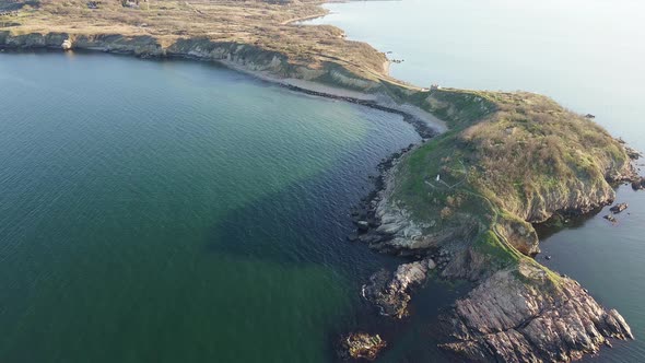 Shore with Grass and Hotels in the Distance Surrounded By the Black Sea Under a Clear Sky alt