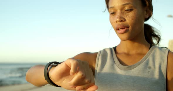 Woman using smartwatch in the beach  alt