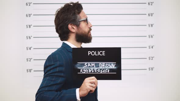 Guilty Businessman in Police Station Posing for Mugshot with Placard alt