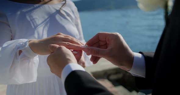 Close up Hands of man and woman exchanging wedding rings, groom and bride standing on ceremony alt