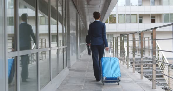 Back View of Young Attractive Businesswoman Walking with Suitcase in Airport alt