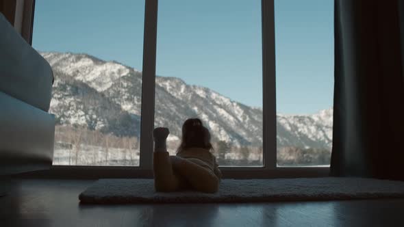 A Small Child Lies on the Floor of the House Near the Window alt