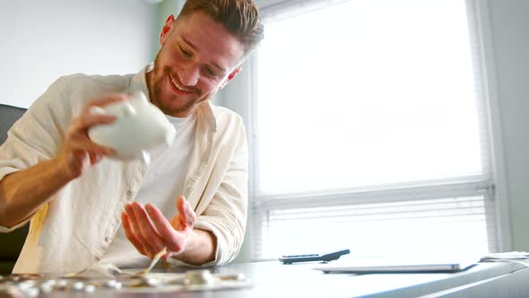 Cheerful guy manager with beard shakes white piggy bank alt