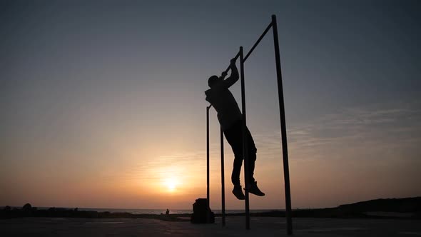 Man Doing Exercises on the Crossbar Against Sunset Background