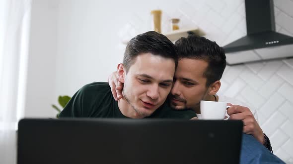 Happy Young Gay Male Couple are Using Laptop pc and Browsing Something alt