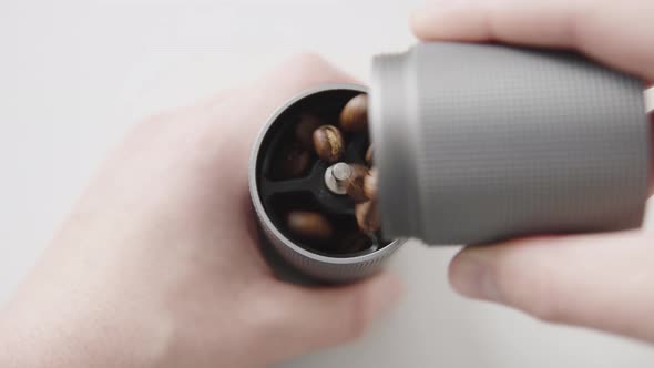 A Man Fills a Coffee Grinder with a Freshly Roasted Arabica Premium Coffee Beans