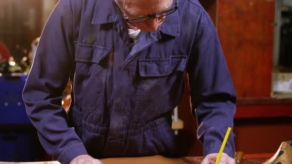 Shoemaker marking a piece of leather with pencil alt