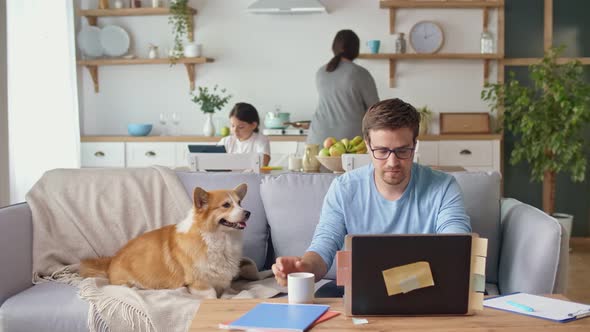 Busy Father Working Remotely with Laptop Sitting in the Kitchen. alt