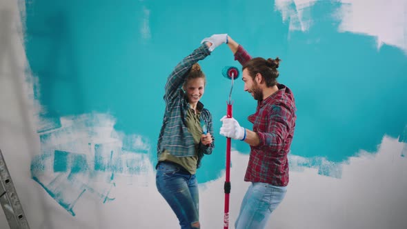 Good Looking Couple at Home While Painting the alt