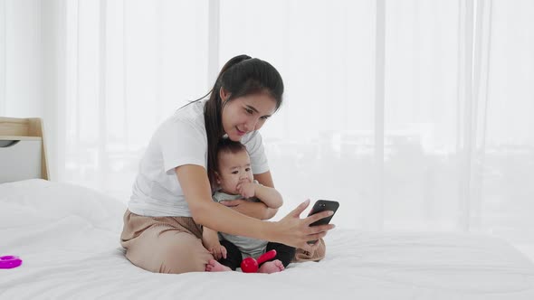 A single mother shows her baby girl to take photos with a smartphone