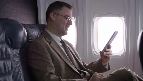 Businessman using digital tablet on airplane