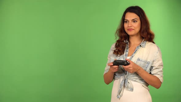 A Caucasian Woman Plays a Game on a Console Off Camera with a Controller in Her Hands  Green Screen