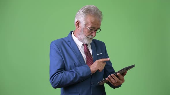 Handsome Senior Bearded Businessman Against Green Background alt
