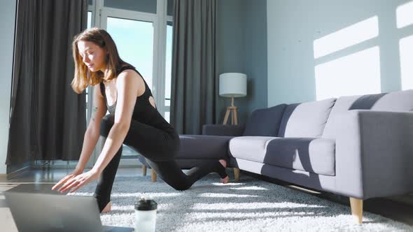 Young Caucasian Woman in Black Jumpsuit Doing Yoga at Home to Develop Flexibility and Balance on the alt