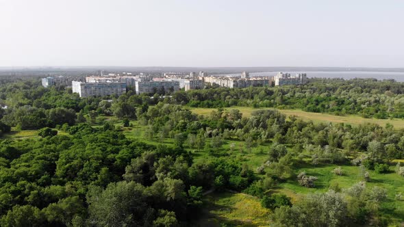 Flying Over a Green Forest Near Near Sleeping Area in Small Town. Summer alt