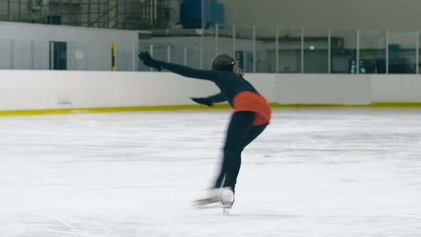 Young figure skater doing sit spin on ice rink