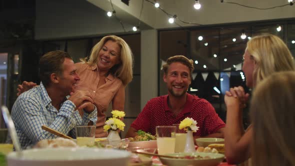 Happy family eating dinner together. alt