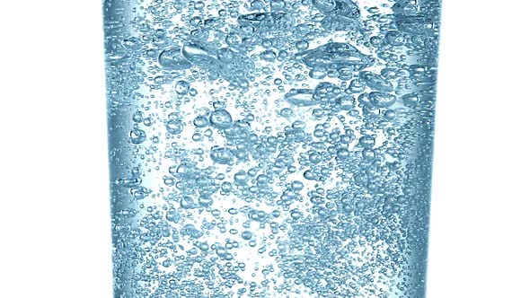 Sparkling Water into Glass against White Background, Slow Motion