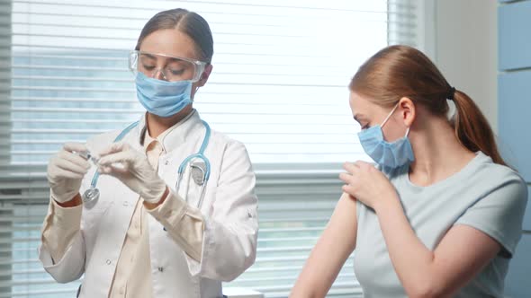 Professional medical nurse in white coat and blue face mask injects alt