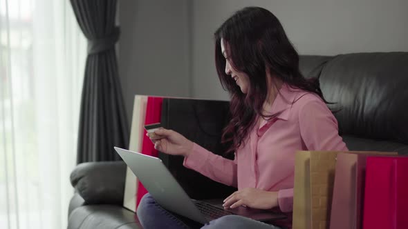 happy woman using laptop computer for online shopping with credit card in the living room
