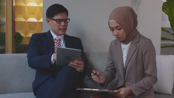 Young asian businessman discussion and planning with secretary while writing document. alt